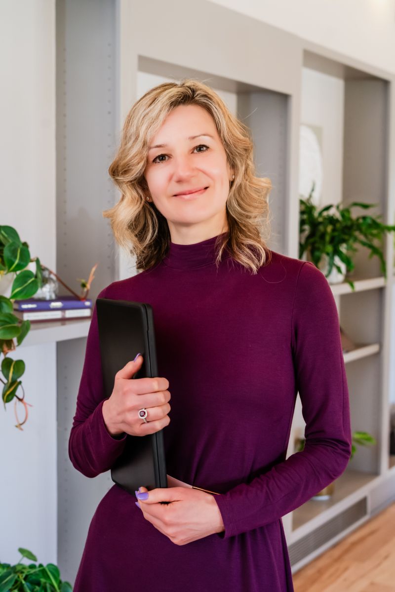 Dasha Tcherniakovskaia standing in a plant-filled room, smiling toward the camera